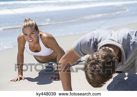 Stock Photo - Woman exercising on the beach with her coach. Fotosearch