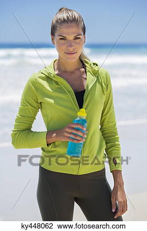 Woman holding a water bottle on the beach View Large Photo Image Stock Image - Woman holding a water bottle on the beach. Fotosearch