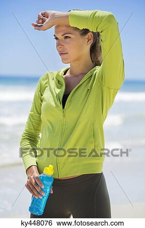 Woman holding a water bottle on the beach View Large Photo Image Stock Photograph - Woman holding a water bottle on the beach. Fotosearch