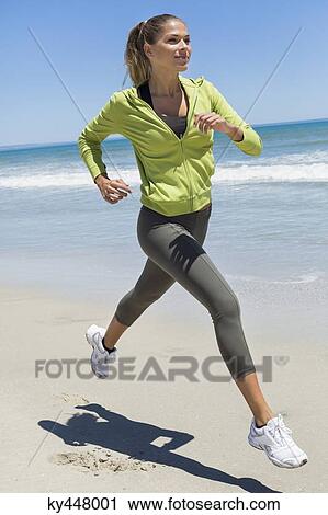Stock Image - Woman jogging on the beach. Fotosearch