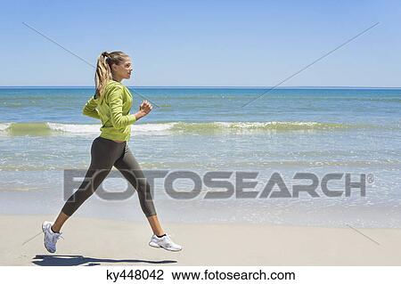 Stock Image - Woman jogging on the beach. Fotosearch