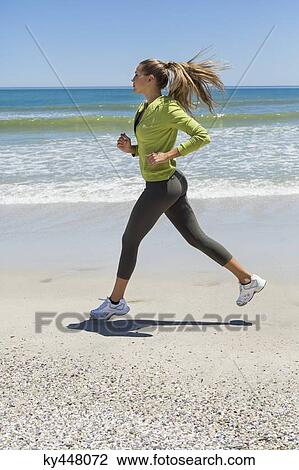 Stock Image - Woman jogging on the beach. Fotosearch