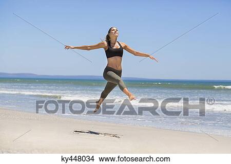 Picture - Woman jumping on the beach. Fotosearch