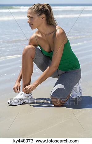 Woman tying her shoelaces on the beach View Large Photo Image Stock Image - Woman tying her shoelaces on the beach. Fotosearch