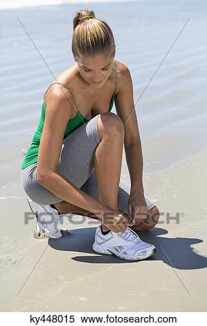 Woman tying her shoelaces on the beach View Large Photo Image Stock Photography - Woman tying her shoelaces on the beach. Fotosearch