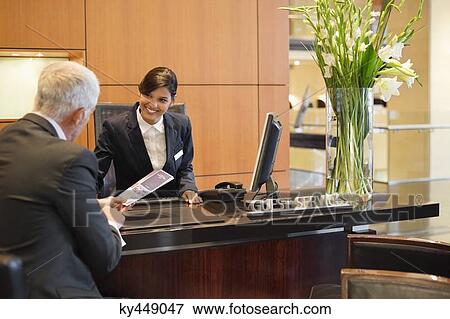 Businessman talking with a receptionist at the hotel reception counter View Large Photo Image Stock Photo - Businessman talking with a receptionist at the hotel reception counter. Fotosearch