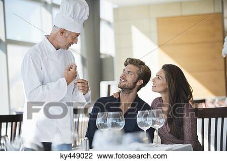 Chef talking to couple at restaurant View Large Photo Image Stock Image - Chef talking to couple at restaurant. Fotosearch