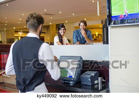 Stock Image - Couple at checkout counter in a restaurant. Fotosearch