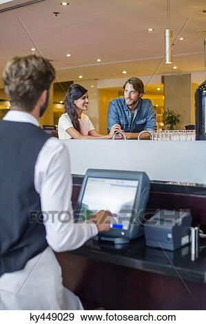 Stock Photo - Couple at checkout counter in a restaurant. Fotosearch