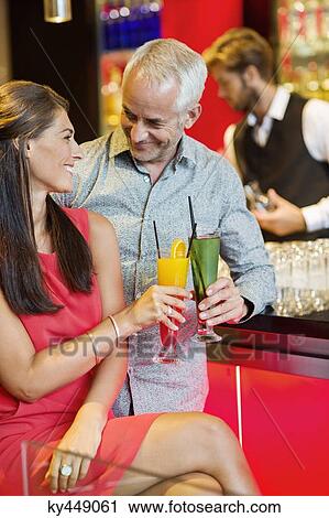 Stock Image - Couple enjoying drinks at the bar counter. Fotosearch