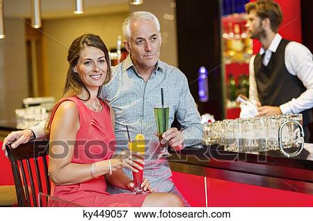 Stock Photo - Couple enjoying drinks at the bar counter. Fotosearch