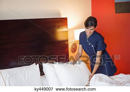 Maid making a bed in a hotel room View Large Photo Image Stock Photo - Maid making a bed in a hotel room. Fotosearch