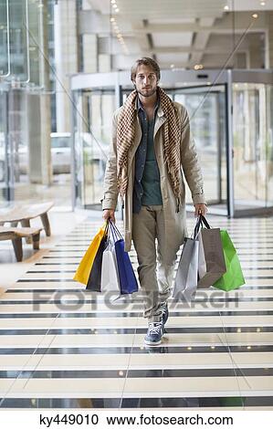 Stock Image - Portrait of a man carrying shopping bags. Fotosearch