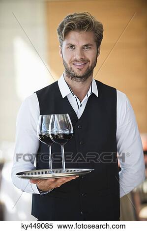 Stock Photography - Portrait of a waiter holding a tray of wine glasses in a restaurant. Fotosearch