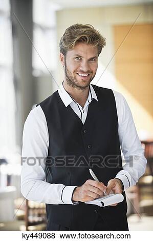 Stock Photo - Portrait of a waiter taking order in a restaurant. Fotosearch