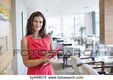 Portrait of a waitress holding a file in a restaurant View Large Photo Image Picture - Portrait of a waitress holding a file in a restaurant. Fotosearch