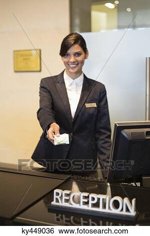Receptionist holding a key card and smiling at the hotel reception counter View Large Photo Image Stock Photograph - Receptionist holding a key card and smiling at the hotel reception counter. Fotosearch