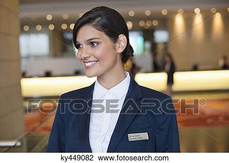 Stock Image - Receptionist smiling in a hotel lobby. Fotosearch