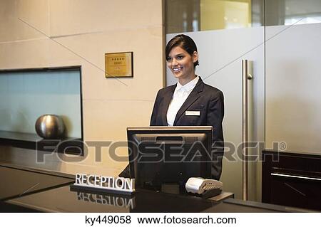 Stock Photo - Receptionist standing at the hotel reception counter and smiling. Fotosearch