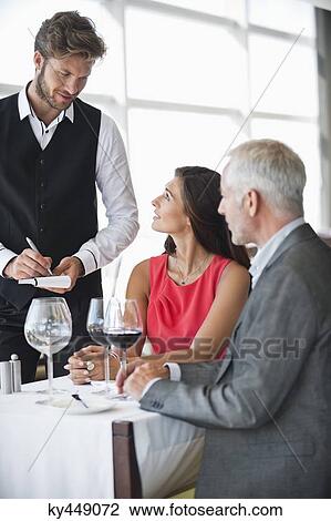Waiter taking orders from a couple in a restaurant View Large Photo Image Stock Image - Waiter taking orders from a couple in a restaurant. Fotosearch
