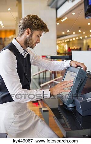 Waiter using a computer at checkout counter in a restaurant View Large Photo Image Stock Photo - Waiter using a computer at checkout counter in a restaurant. Fotosearch