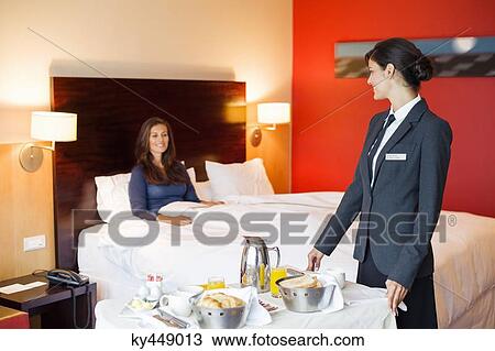 Waitress serving food to a woman in a hotel room View Large Photo Image Stock Image - Waitress serving food to a woman in a hotel room. Fotosearch
