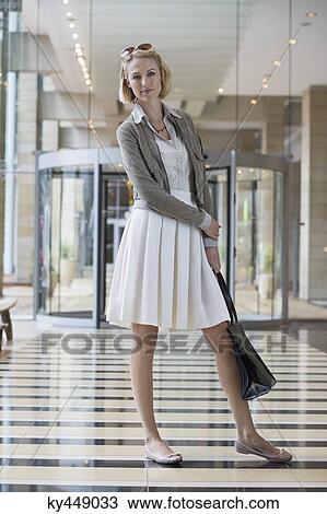 Woman standing on an airport holding a leather handbag View Large Photo Image Stock Image - Woman standing on an airport holding a leather handbag. Fotosearch