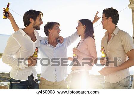 Stock Image - Four friends enjoying beer in party. Fotosearch