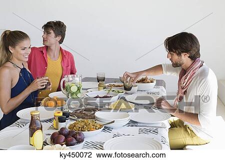 Friends eating lunch at dining table View Large Photo Image Stock Image - Friends eating lunch at dining table. Fotosearch
