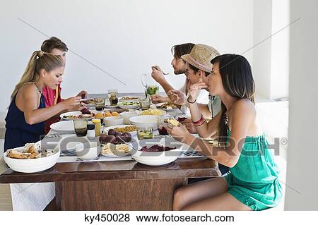 Friends eating lunch at dining table View Large Photo Image Stock Photo - Friends eating lunch at dining table. Fotosearch