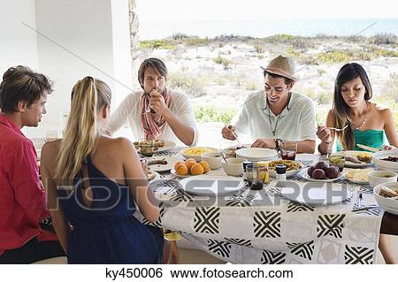 Friends eating lunch at dining table View Large Photo Image Stock Photograph - Friends eating lunch at dining table. Fotosearch