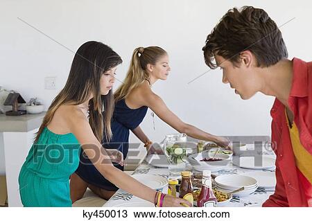 Friends setting a dining table View Large Photo Image Stock Image - Friends setting a dining table. Fotosearch