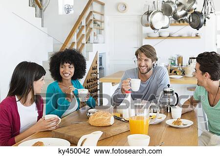 Friends sitting at a dining table having breakfast View Large Photo Image Stock Image - Friends sitting at a dining table having breakfast. Fotosearch
