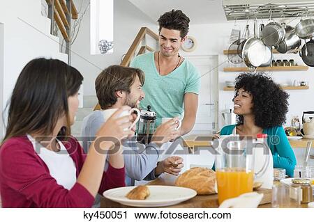Friends sitting at a dining table having breakfast View Large Photo Image Stock Image - Friends sitting at a dining table having breakfast. Fotosearch
