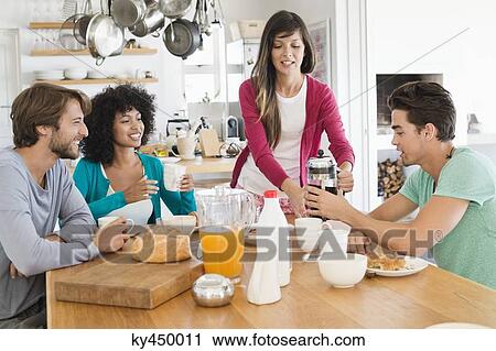 Friends smiling at a dining table View Large Photo Image Stock Image - Friends smiling at a dining table. Fotosearch