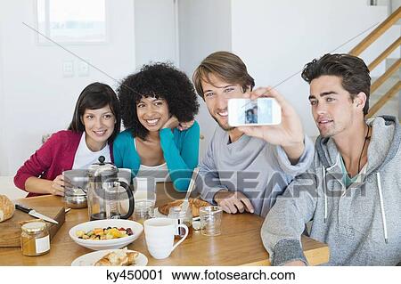 Stock Image - Friends taking picture of themselves with a mobile phone. Fotosearch