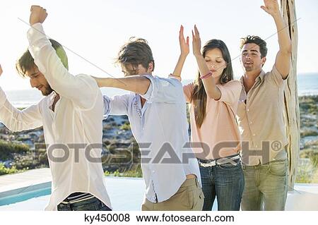 Stock Photo - Group of friends dancing at the poolside. Fotosearch