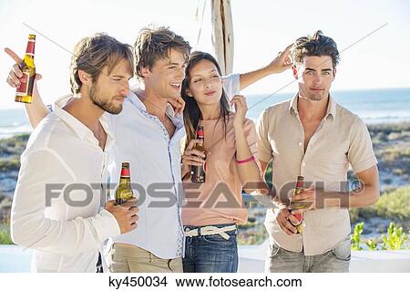 Picture - Group of friends enjoying beer outdoors on vacation. Fotosearch