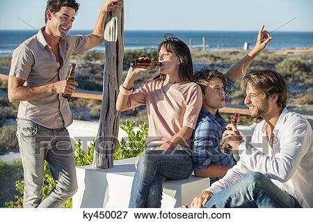 Stock Photo - Group of friends enjoying beer outdoors on vacation. Fotosearch