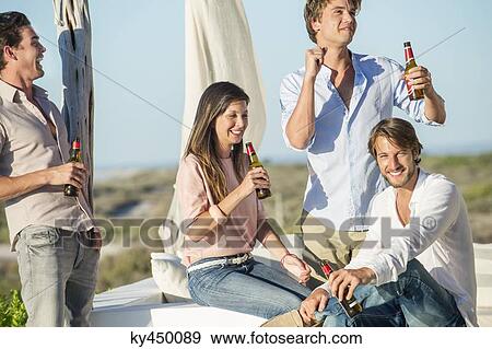 Group of friends enjoying beer outdoors on vacation View Large Photo Image Stock Photo - Group of friends enjoying beer outdoors on vacation. Fotosearch
