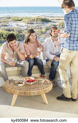 Picture - Group of friends enjoying drinks outdoors on vacation. Fotosearch