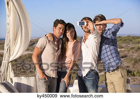 Group of friends photographing themselves with a mobile phone View Large Photo Image Stock Photo - Group of friends photographing themselves with a mobile phone. Fotosearch