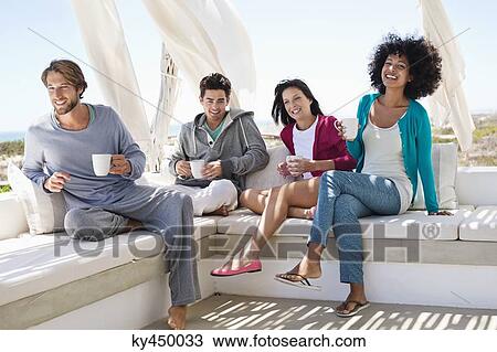 Stock Image - Smiling friends enjoying coffee on the terrace. Fotosearch