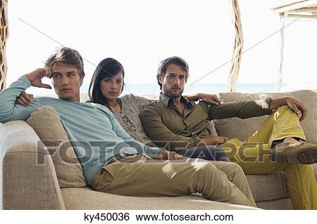 Stock Photograph - Three friends sitting together on a couch. Fotosearch