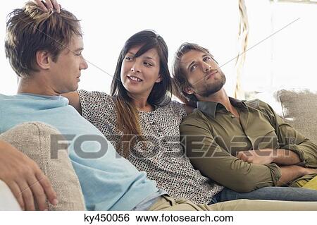Three friends sitting together on a couch View Large Photo Image Stock Photograph - Three friends sitting together on a couch. Fotosearch