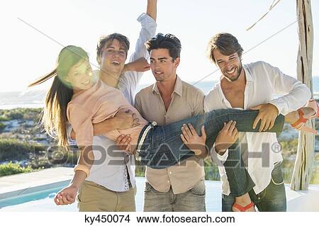 Three men lifting their female friend at the poolside View Large Photo Image Picture - Three men lifting their female friend at the poolside. Fotosearch