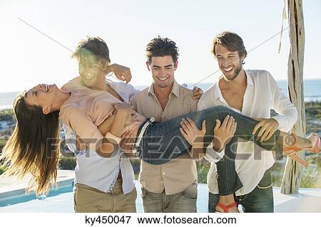 Three men lifting their female friend at the poolside View Large Photo Image Stock Photo - Three men lifting their female friend at the poolside. Fotosearch