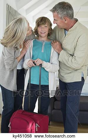 Boy holding a suitcase with his grandparents at home View Large Photo Image Stock Photo - Boy holding a suitcase with his grandparents at home. Fotosearch