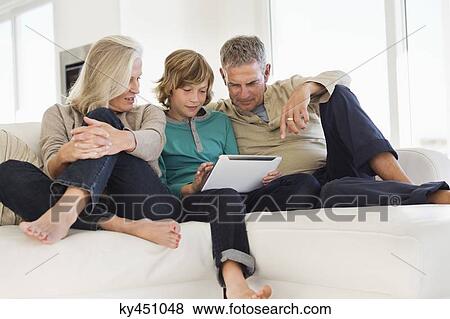 Boy using a digital tablet with his grandparents on a couch View Large Photo Image Stock Photo - Boy using a digital tablet with his grandparents on a couch. Fotosearch