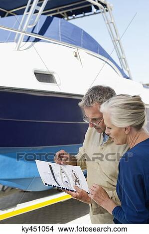 Couple reading a brochure near a yacht View Large Photo Image Picture - Couple reading a brochure near a yacht. Fotosearch